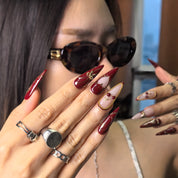 Cherry Bite press-on nails detail – high-shine glossy finish with 3D cherry and gold ribbon on burgundy base