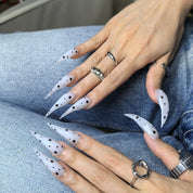 Close-up of Cat Claw #9 press-on nails — soft milky white translucent base hand-painted black polka dot varying sizes nail art by Poorguyshop
