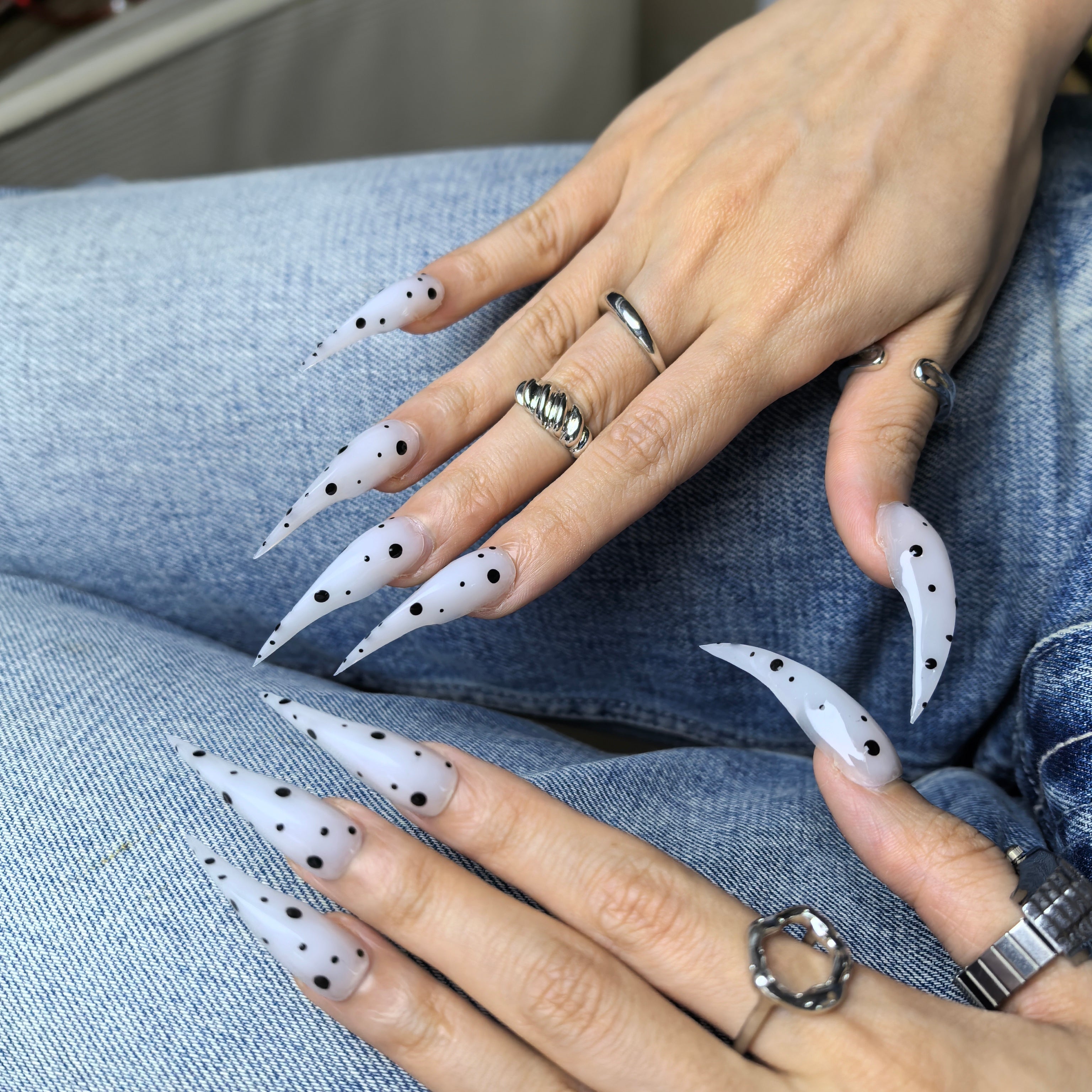Close-up of Cat Claw #9 press-on nails — soft milky white translucent base hand-painted black polka dot varying sizes nail art by Poorguyshop