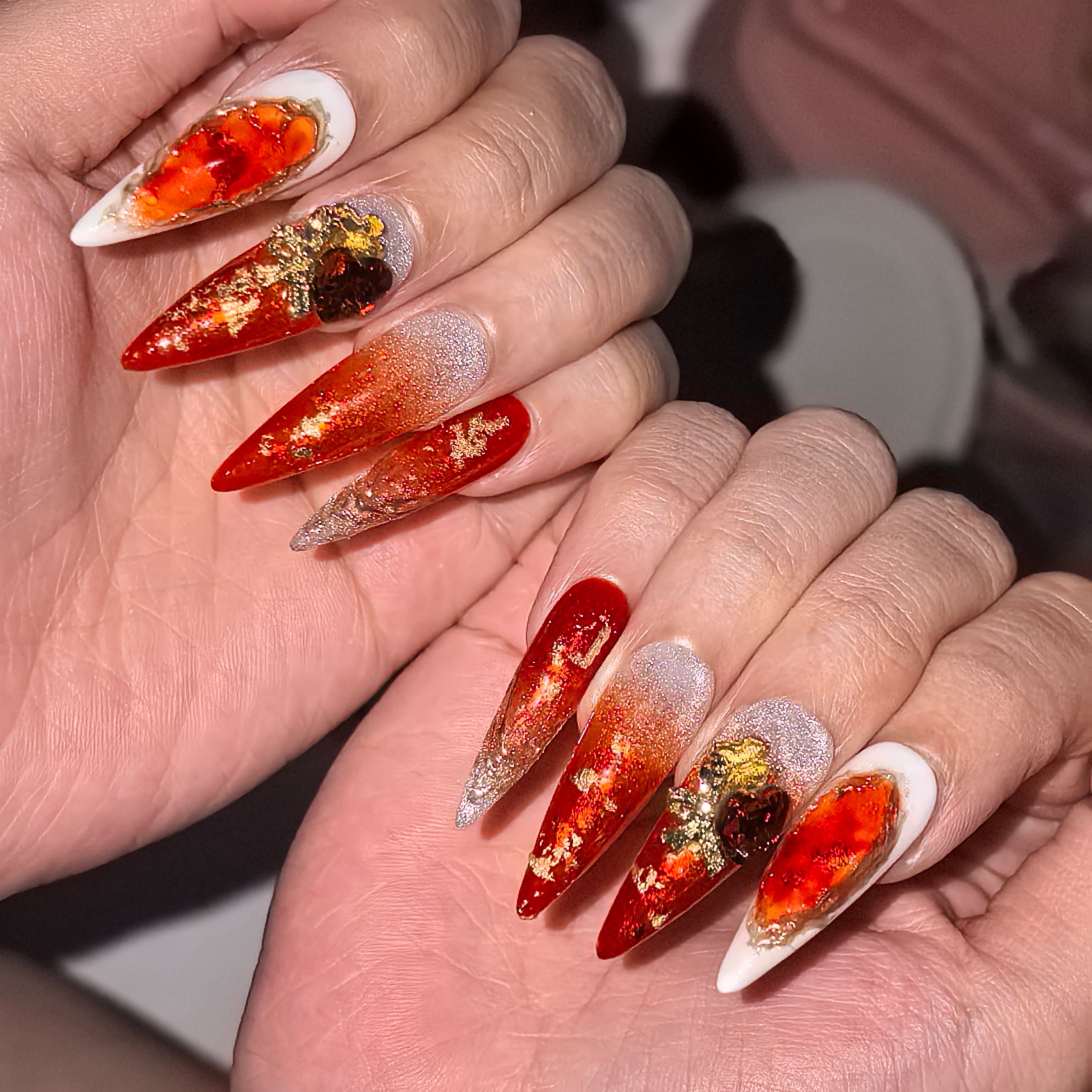Close-up of Twilight Ember press-on nails — large citrine gem embellishment gold foil flake molten metal lava accent ruby red gradient nail art by Poorguyshop