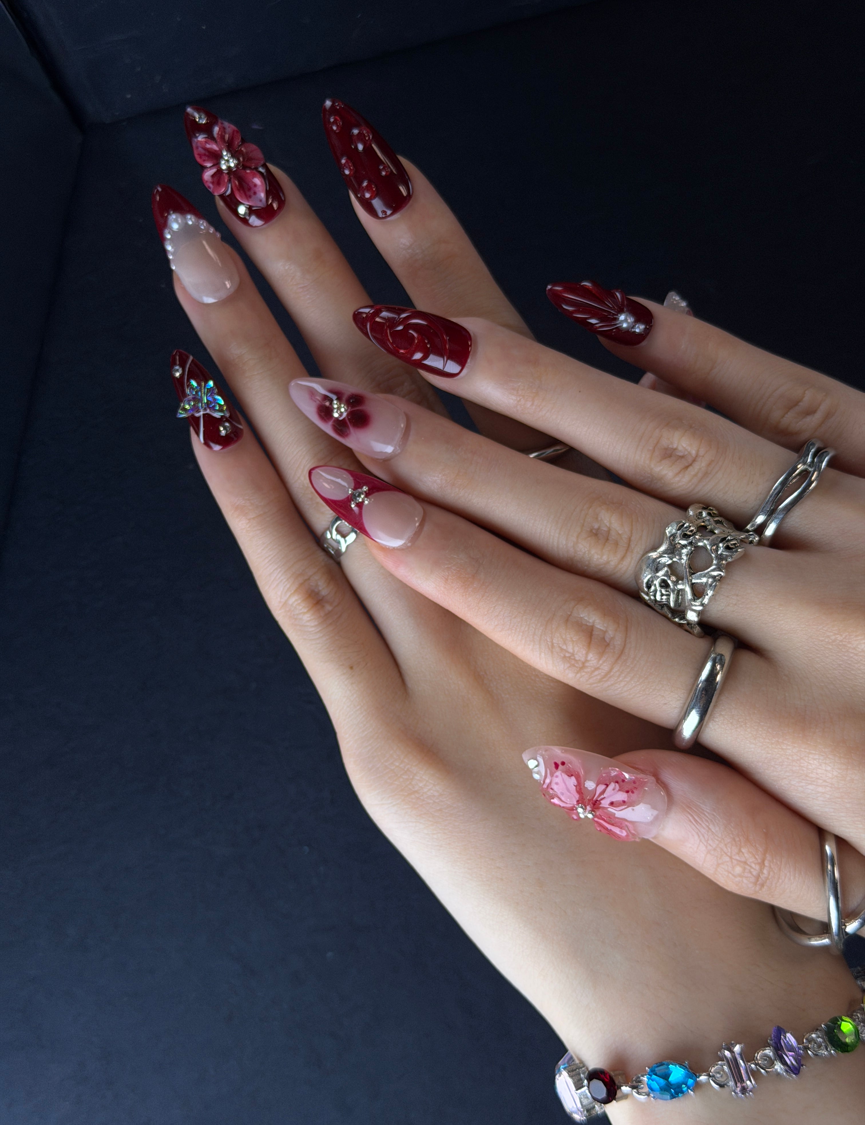 Crimson Petal press-on nails close-up – 3D pink floral charms with sparkling crystal centers on burgundy gradient base