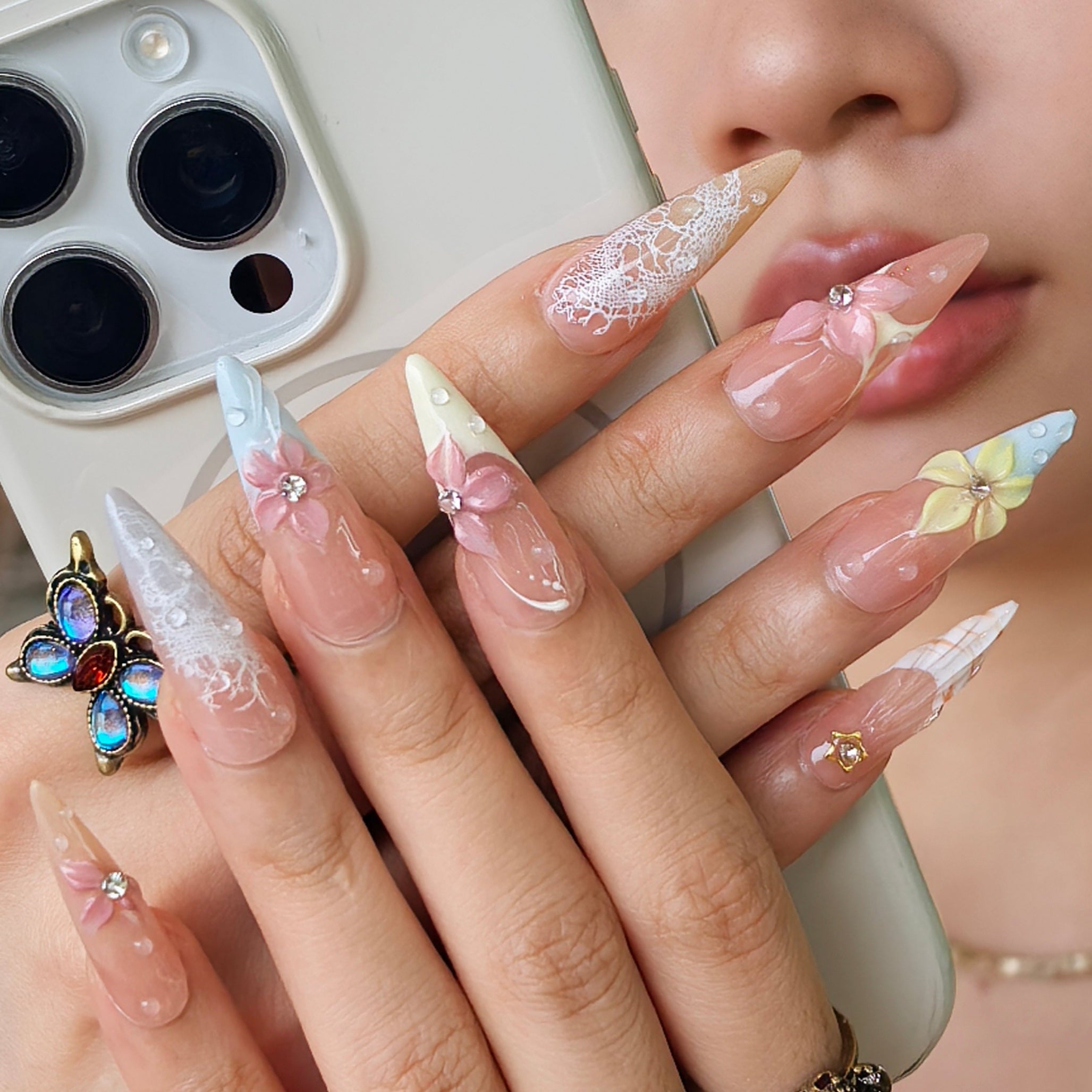 Floral press-on nails close-up – sparkling gemstone centers and star accents on pastel floral stiletto nails