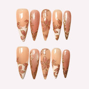 PoorGuyShop Blush Petal handmade stiletto press-on nails – soft peachy base with gold-outlined floral patterns and shimmer accents, 25–30mm