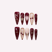 PoorGuyShop Cherry Bite handmade stiletto press-on nails – deep burgundy base with 3D cherry charms and gold ribbon swirl accents