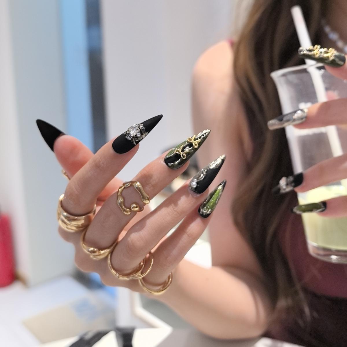Woman wearing Nightmoss handmade press-on nails — black gold silver pearl butterfly bow nail art coffin stiletto by Poorguyshop